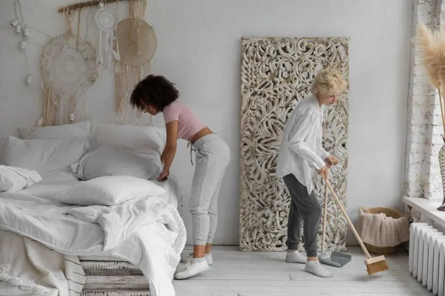 Two cleaners making a bed during a move-out or Airbnb turnover cleaning in Detroit